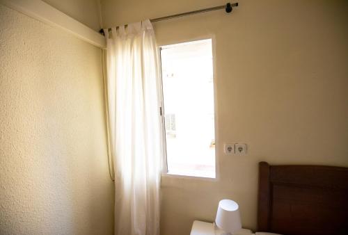 マドリードにあるHostal Los Peralesの白いカーテン付きの部屋の窓