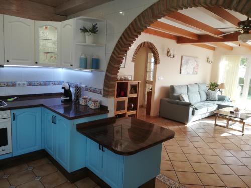 ベナルマデナにあるFinca Villordo Villa Tranquilaのキッチン(青いキャビネット付)、リビングルーム(ソファ付)