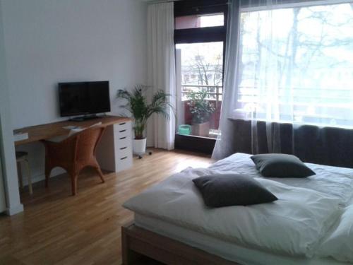 a bedroom with a bed and a desk and a television at Apartment B311 mit Pool in Lahnstein