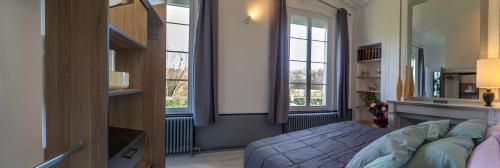 a bedroom with a bed and two windows at Chambre d'Hôtes Les Jardins de Marie, SCI Charles III in Bernay