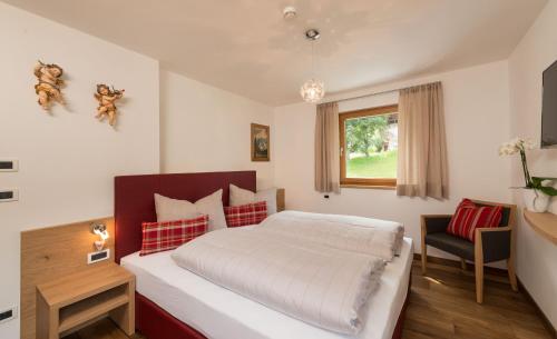 a bedroom with a bed and a desk and a window at Alpin Sport in Ortisei