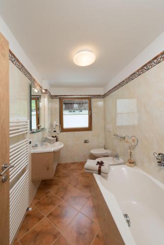 a bathroom with a tub and a toilet and a sink at Alpin Sport in Ortisei