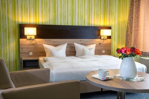 um quarto com uma cama e uma mesa com um vaso de flores em Appart Hotel Roßdorf em Roßdorf