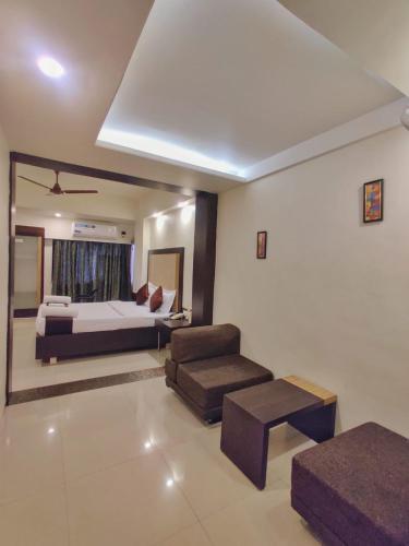 a bedroom with a bed and a chair and a couch at Hotel Ashwin Igatpuri, Pure Veg & Jain Food in Igatpuri