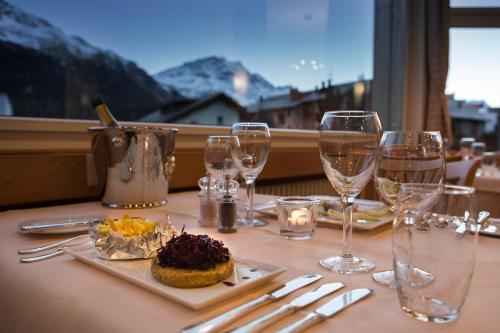 a table with wine glasses and a plate of food at Appartamenti presso Hotel Europa in St. Moritz