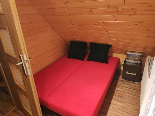 a red bed in a wooden cabin with two pillows at Dom wakacyjny nad jeziorem - Willa Mira in Zarzecze