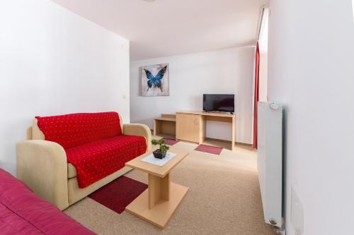 a living room with a red couch and a table at Hotel Center Bohinjsko Jezero in Bohinj