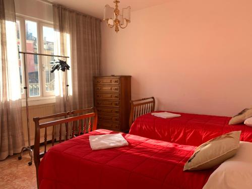 a bedroom with two beds with red sheets and a dresser at Appartamento Dante Alighieri in Levanto