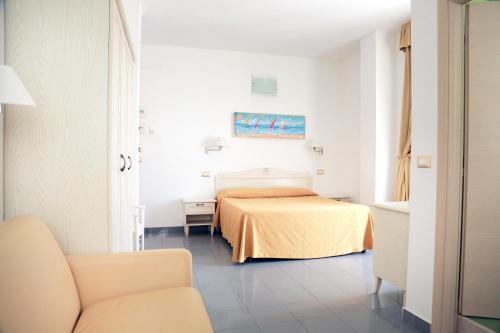 a hotel room with a bed and a chair at Hotel Marechiaro - Direttamente sul mare in Vico del Gargano