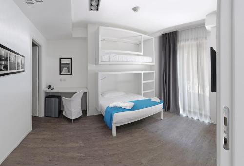 a white bedroom with a bed and a desk at Hotel Europa Monetti in Cattolica