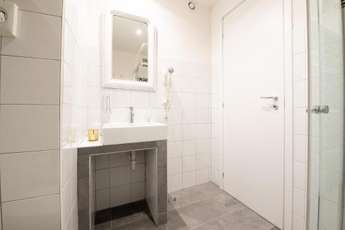 a white bathroom with a sink and a mirror at LE MADAMINE ROOMS in Turin