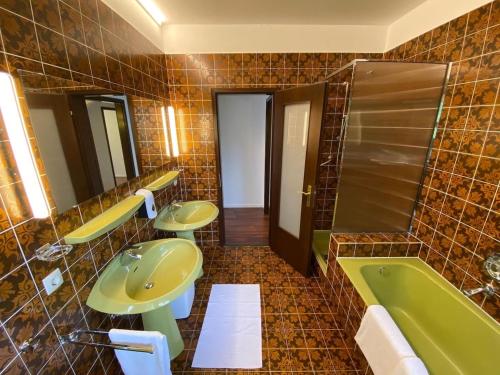 a tiled bathroom with two sinks and a tub at Bodensee Bungalow in Immenstaad am Bodensee