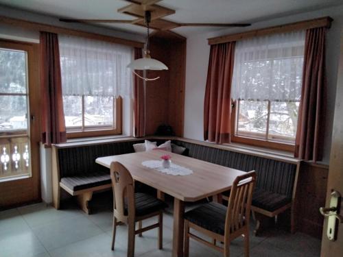 a dining room with a table and chairs and windows at Nagelehof in Ainet