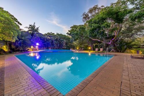 a swimming pool with blue water in a park at Sanbonani Hotel in Hazyview