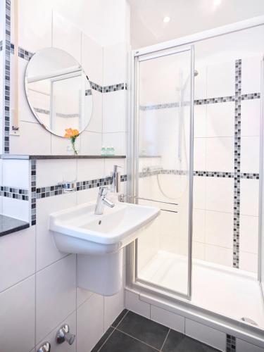 a white bathroom with a sink and a shower at Portofino in Bonn