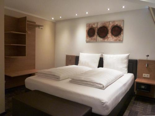1 dormitorio con 1 cama con sábanas y almohadas blancas en Hotel Saline 3-Sterne Superior en Büdingen