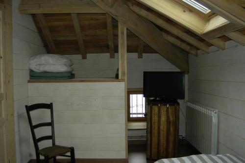 Habitación con cama, TV y silla. en Chambres d'Hotes Au Vieux Logis en Nistos