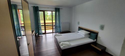 a room with two beds and a door to a balcony at Popasul din Lunca in Pui