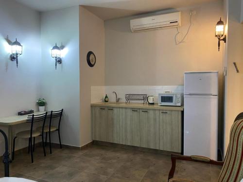 a kitchen with a table and a white refrigerator at Hotel Rehovot in Rechovot