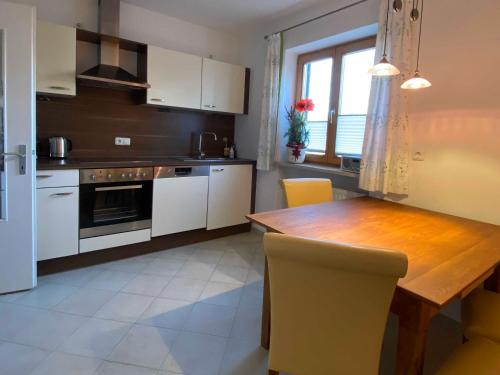 a kitchen with a wooden table and white cabinets at Ferienwohnung Hermann in Fischbachau