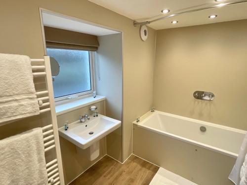 a bathroom with a sink and a bath tub at Smithy House in Tongue