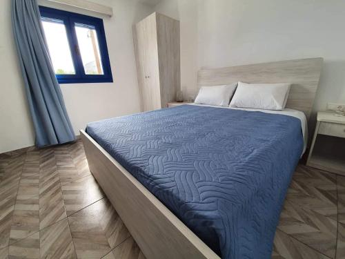 um quarto com uma cama com um edredão azul e uma janela em EDEM HOUSE FINIKAS em Loutró