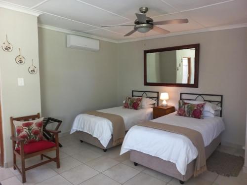 2 Betten in einem Zimmer mit einem Spiegel und einem Stuhl in der Unterkunft Karoo Life B&B in Calitzdorp