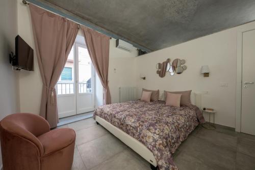 a bedroom with a bed and a chair and a window at Casta Diva Luxury Apartments in Palermo