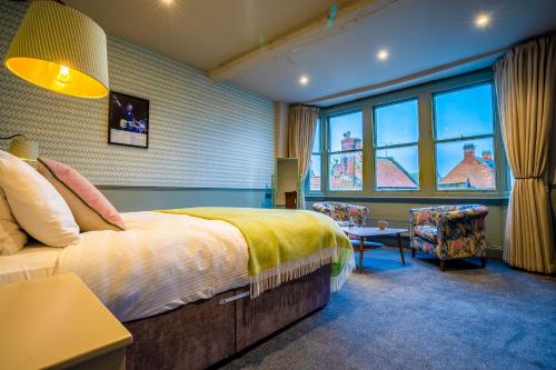 1 dormitorio con 1 cama, 1 silla y ventanas en The Crown Hotel en Glastonbury