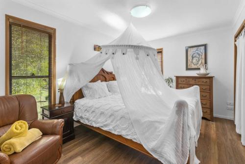 1 dormitorio con 1 cama con mosquitera en Cosy Romantic Cottage, en Tallebudgera