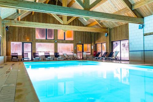 une grande piscine avec des chaises dans un bâtiment dans l'établissement Madame Vacances Les Chalets du Berger Premium***, à La Féclaz