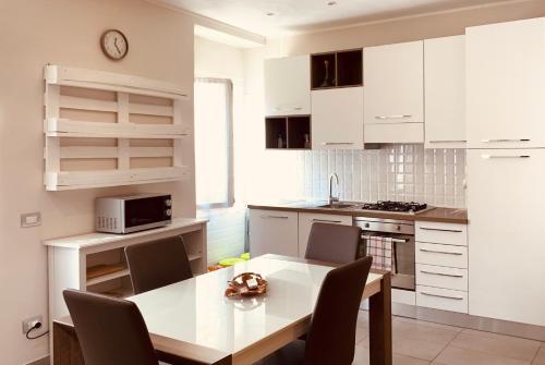 een keuken met witte kasten en een tafel met stoelen bij Appartamenti Sant Andrea in Levanto