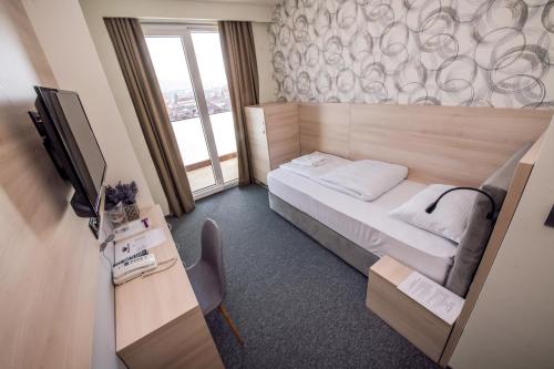 a small room with a bed and a television at Zlatna Kruna in Banja Luka