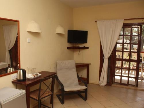 a living room with a table and a chair and a television at Lemon Creek Hotel Resort in Bijilo