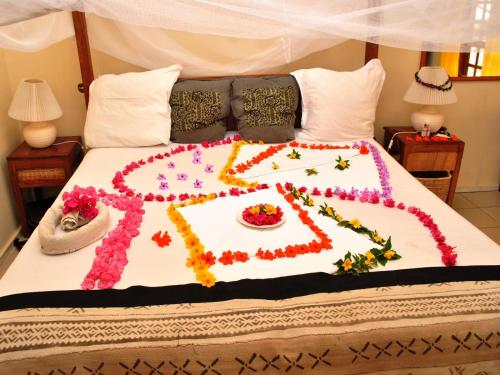 a cake on a bed with flowers on it at Lemon Creek Hotel Resort in Bijilo
