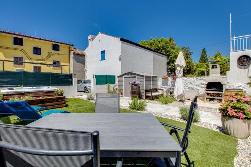 a patio with a table and chairs in a yard at Apartments Mikulin Family in Punat