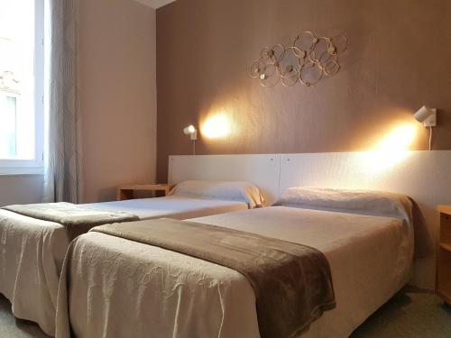 two beds in a hotel room with a chandelier at Hôtel de Provence in Brignoles