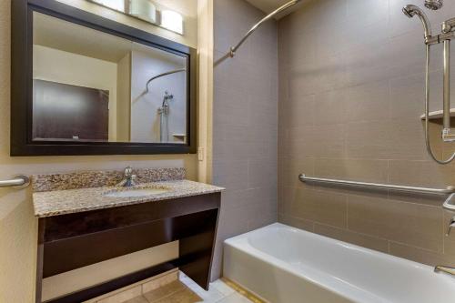 a bathroom with a tub and a sink and a mirror at Comfort Inn Bentonville - Crystal Bridges in Bentonville