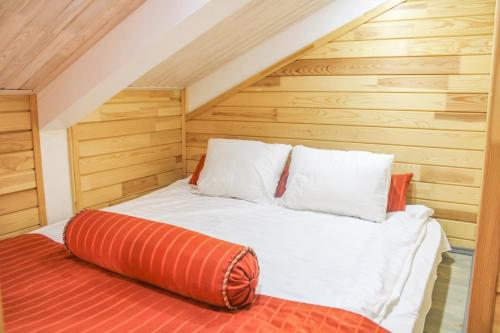 Bett mit orangefarbenem und weißem Kissen in einem Zimmer in der Unterkunft ЭТНО-комплекс Тургояк in Turgoyak