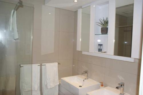 - une salle de bains blanche avec deux lavabos et un miroir dans l'établissement Casa Bonita, à Gaborone