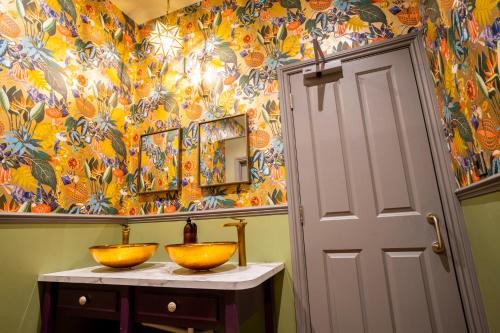a bathroom with two bowls on a counter with a colorful wall at The Crown Hotel in Glastonbury