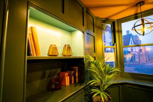 a book shelf with books and bells next to a window at The Crown Hotel in Glastonbury