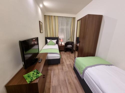 a hotel room with two beds and a flat screen tv at Auenwald Hotel und Apartmenthaus in Leipzig