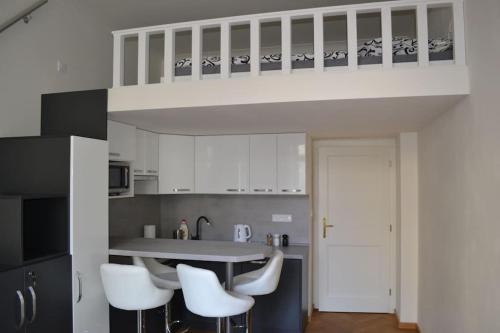 a kitchen with white cabinets and a table with white chairs at quiet apartment in a short distance from the city in Prague