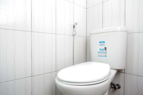 a white toilet in a bathroom with white tiles at KoolKost Syariah near Malioboro Area in Yogyakarta