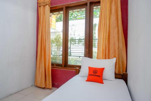 Dormitorio con cama con almohada naranja en KoolKost Syariah near Malioboro Area, en Yogyakarta