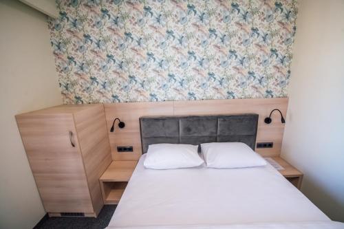 a small bedroom with a bed and a floral wallpaper at Zlatna Kruna in Banja Luka