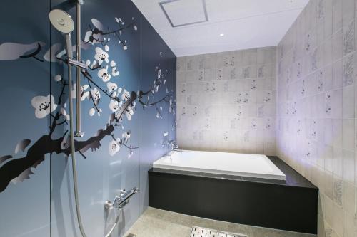 a bathroom with a shower and a bathtub with a tree mural at HOTEL 粋 in Fukuyama