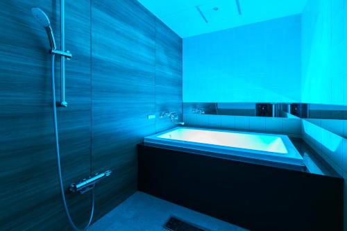 a bathroom with a tub and a shower with blue lighting at HOTEL 粋 in Fukuyama