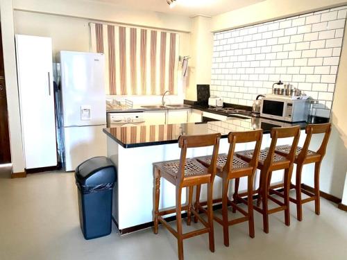 eine Küche mit einem Tisch und Stühlen sowie einem Kühlschrank in der Unterkunft ALL SAINTS ON ROBERTS in Pietermaritzburg